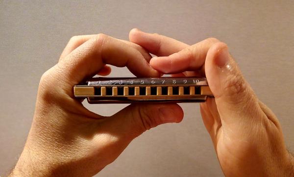 2 mains en position pour jouer de l'harmonica diatonique